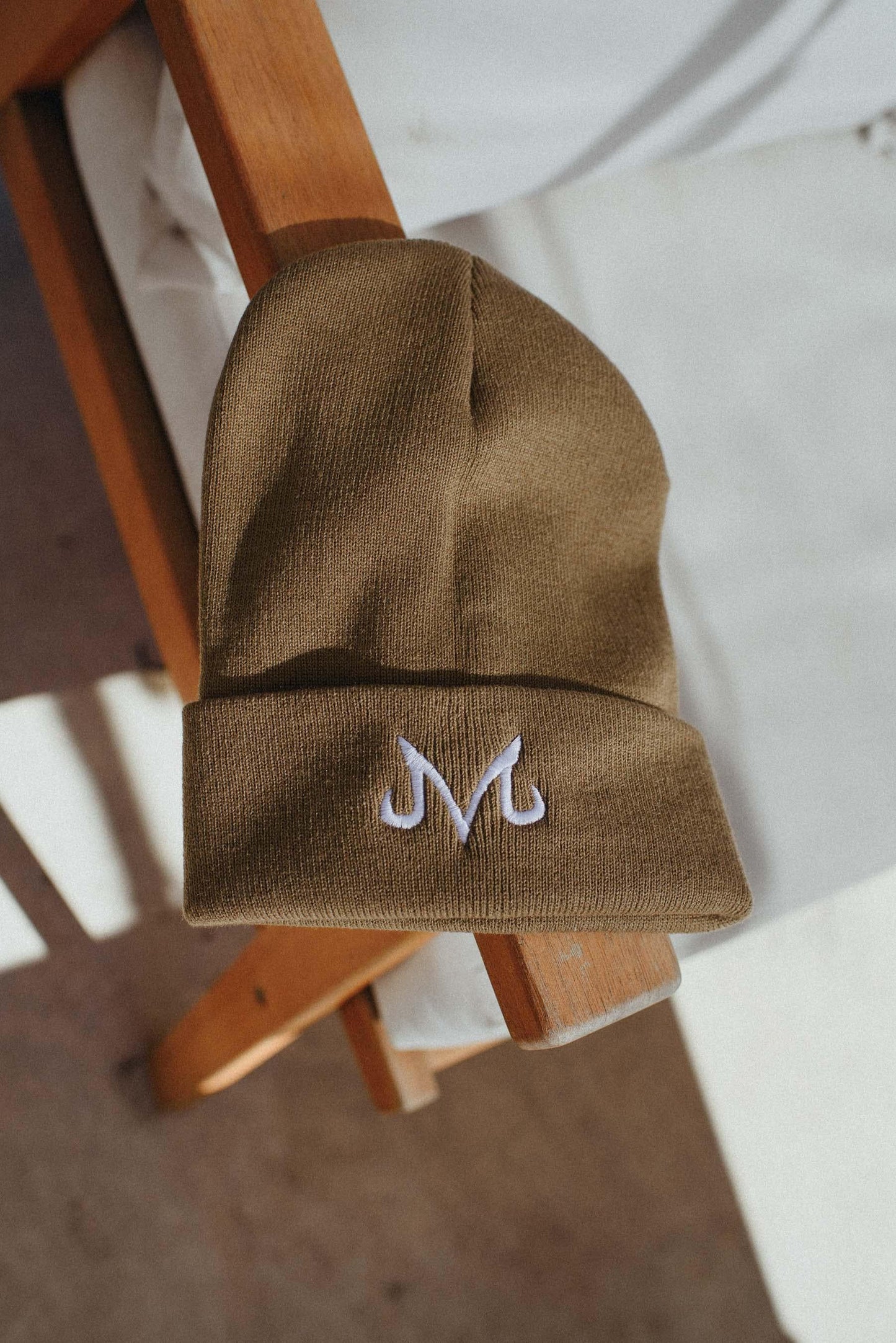 May include: A brown beanie with a white embroidered 'M' logo.