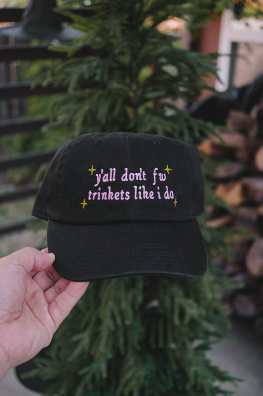 Black cap with text held by a hand against a blurred natural background
