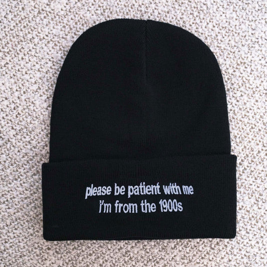 May include: Black beanie with white embroidered text that reads "please be patient with me I'm from the 1900s"