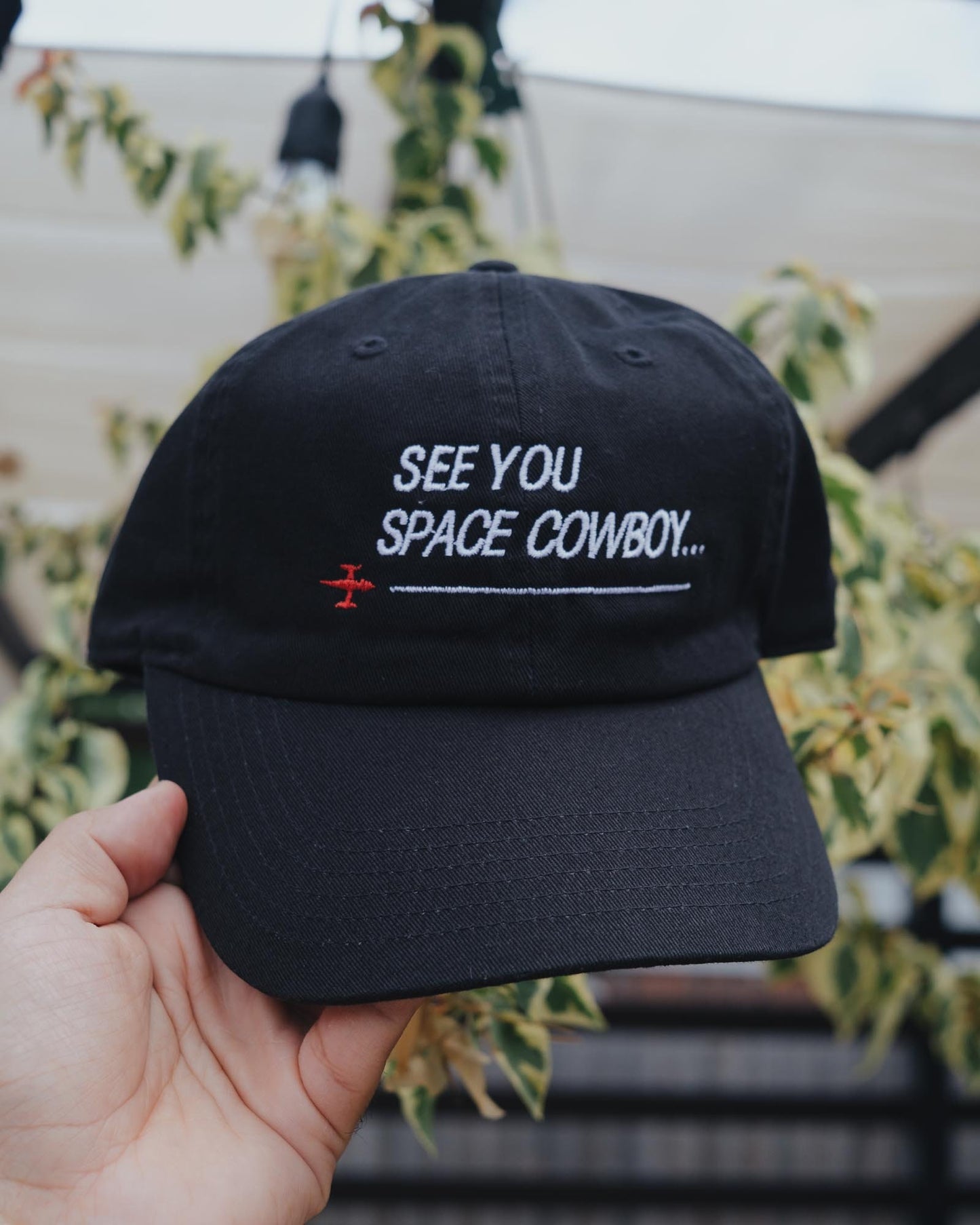 May include: Black baseball cap with white embroidery that reads "See You Space Cowboy..." with a small red airplane symbol.