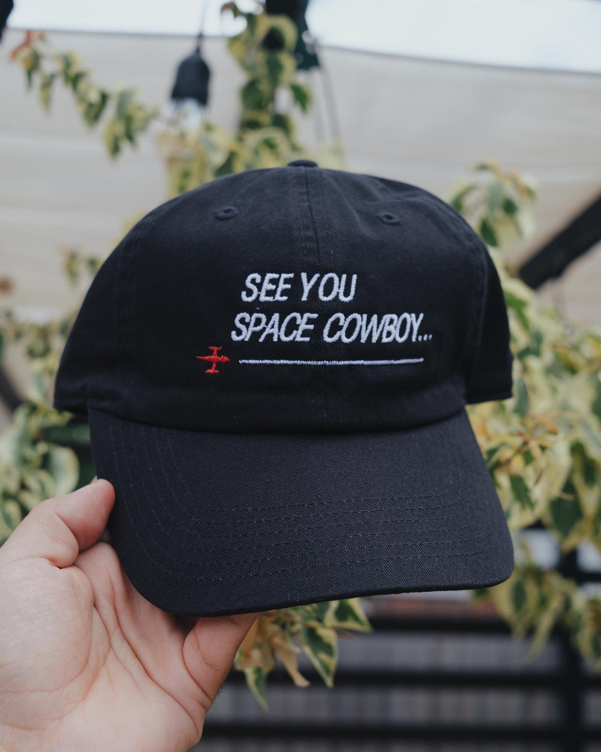 May include: Black baseball cap with white embroidery that reads "See You Space Cowboy..." with a small red airplane symbol.